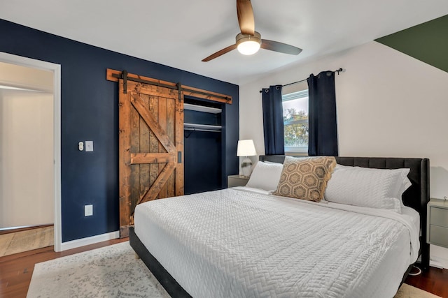 bedroom featuring a closet, a barn door, hardwood / wood-style flooring, and ceiling fan