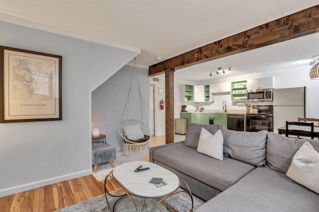 living room featuring beam ceiling, light hardwood / wood-style floors, wooden ceiling, and sink