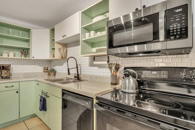 kitchen with backsplash, black appliances, sink, green cabinetry, and light tile patterned flooring