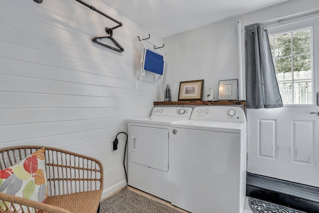 laundry area featuring separate washer and dryer, wooden walls, and light tile patterned floors