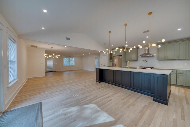 kitchen featuring visible vents, light countertops, a notable chandelier, stainless steel fridge, and wall chimney exhaust hood