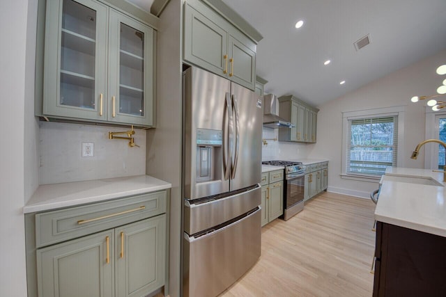 kitchen featuring visible vents, a sink, stainless steel appliances, light countertops, and wall chimney exhaust hood