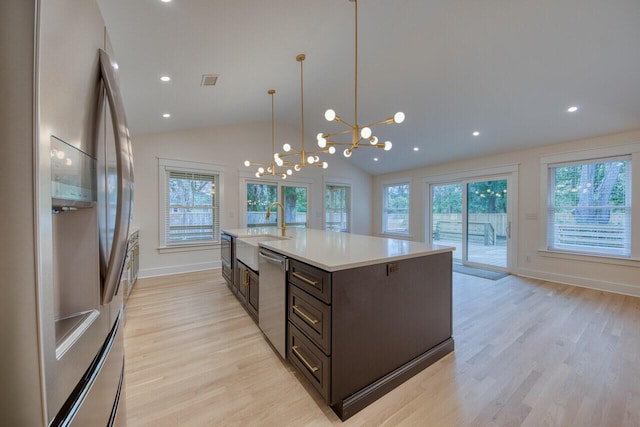 kitchen featuring light wood-style flooring, a sink, light countertops, appliances with stainless steel finishes, and a notable chandelier