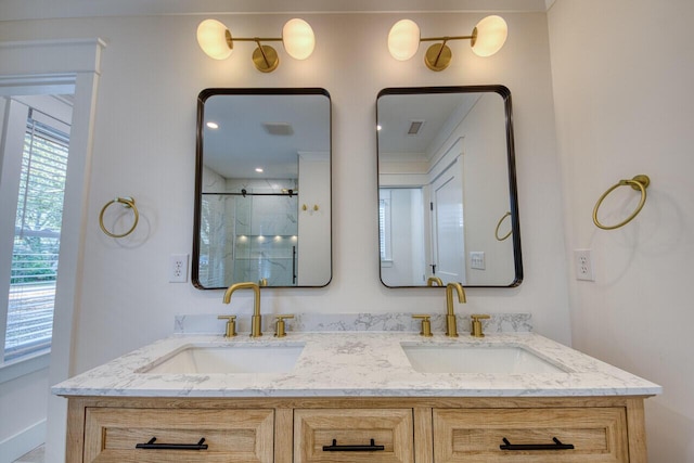 full bath featuring a sink, an enclosed shower, visible vents, and double vanity