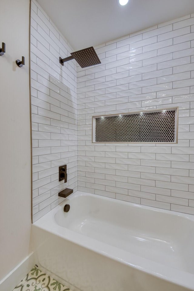 bathroom featuring tile patterned flooring, tub / shower combination, and baseboards