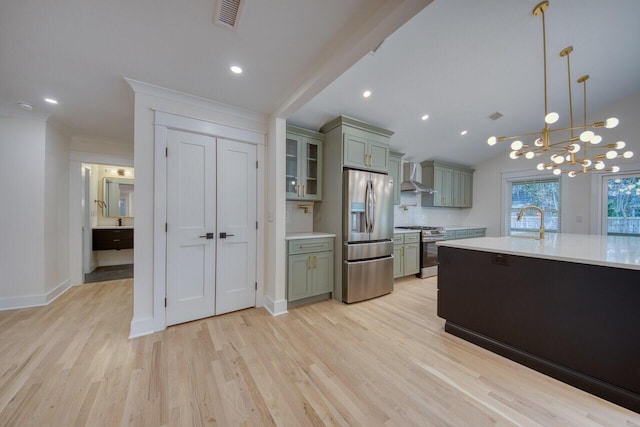 kitchen with visible vents, a sink, light countertops, appliances with stainless steel finishes, and wall chimney range hood