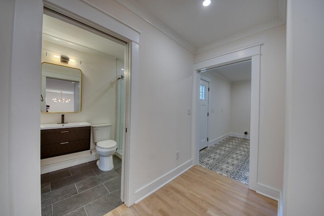 bathroom with baseboards, toilet, wood finished floors, vanity, and a shower