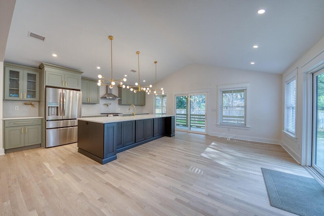 kitchen featuring visible vents, a healthy amount of sunlight, light countertops, lofted ceiling, and stainless steel refrigerator with ice dispenser