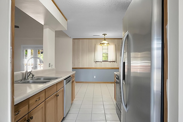 kitchen with appliances with stainless steel finishes, a textured ceiling, sink, hanging light fixtures, and light tile patterned flooring