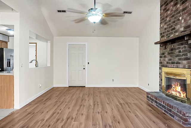 unfurnished living room featuring ceiling fan, light hardwood / wood-style floors, a fireplace, and vaulted ceiling