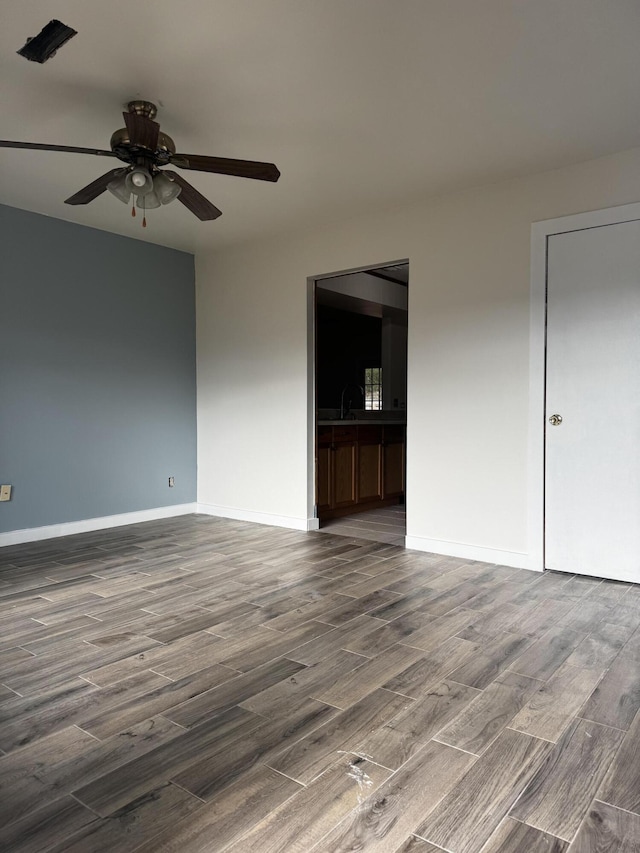 unfurnished room featuring dark hardwood / wood-style floors, ceiling fan, and sink