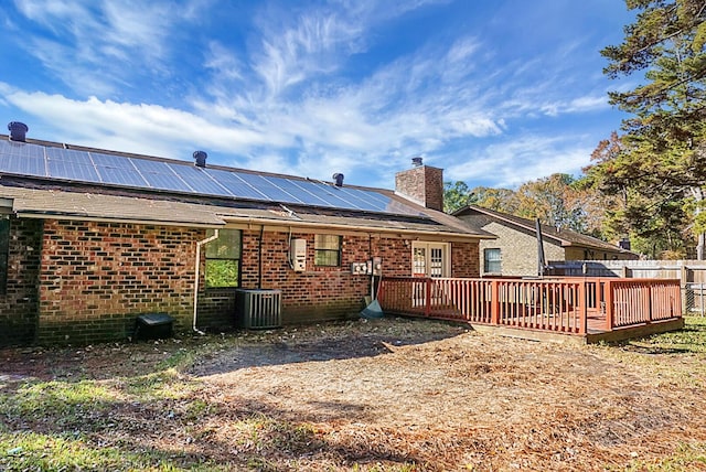 back of property with solar panels, cooling unit, and a wooden deck