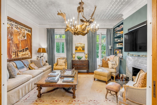 sitting room with a premium fireplace, plenty of natural light, crown molding, and a chandelier