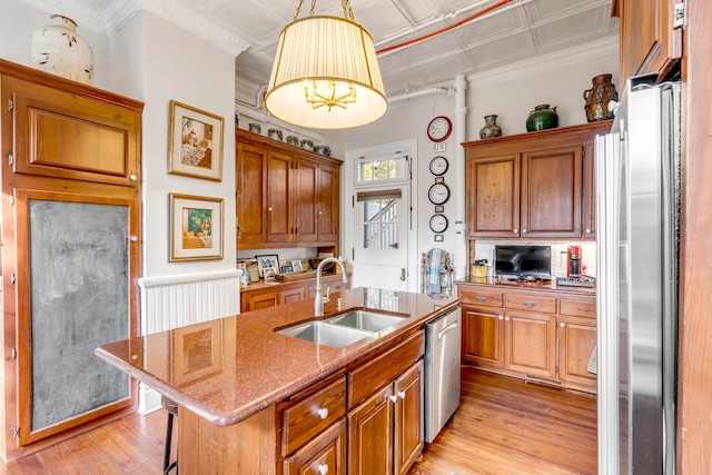 kitchen featuring decorative light fixtures, an island with sink, sink, a breakfast bar area, and stainless steel appliances