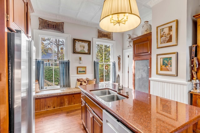 kitchen featuring sink, hanging light fixtures, light stone counters, stainless steel appliances, and light wood-type flooring