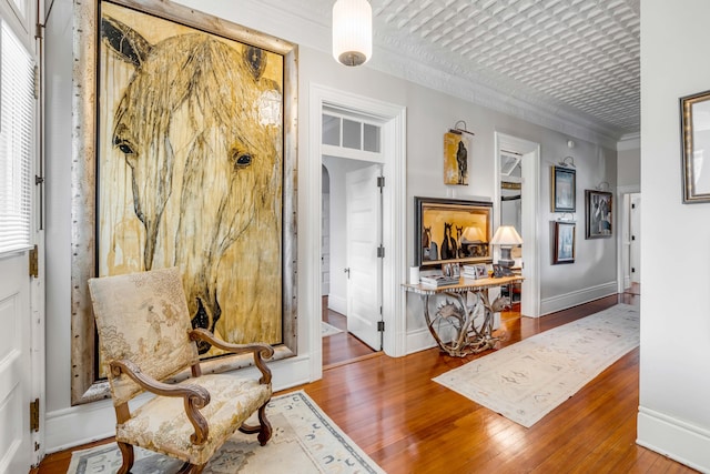 sitting room with hardwood / wood-style flooring and crown molding