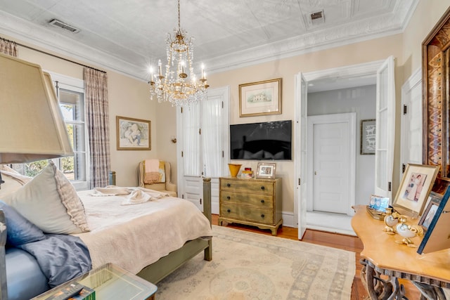 bedroom featuring an inviting chandelier, crown molding, and wood-type flooring