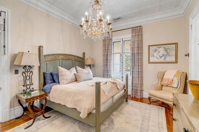 bedroom featuring crown molding, an inviting chandelier, and light hardwood / wood-style floors