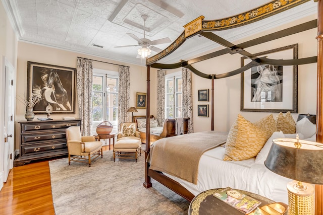 bedroom featuring ceiling fan, ornamental molding, and wood-type flooring