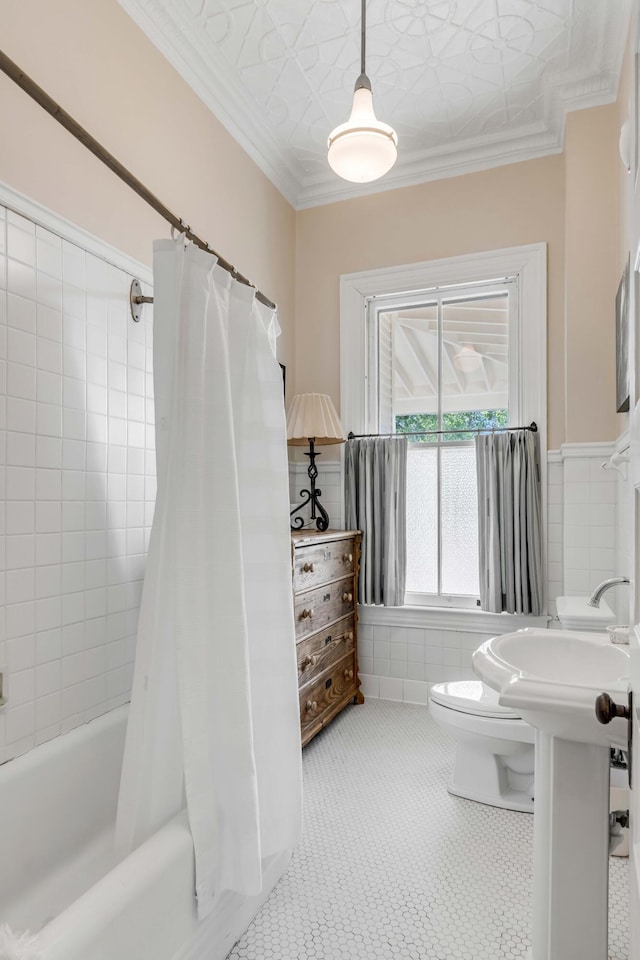 bathroom with ornamental molding, tile walls, shower / bath combination with curtain, and toilet