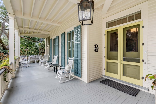 wooden terrace with outdoor lounge area, french doors, and a porch