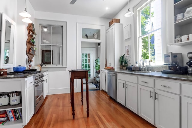 kitchen with white cabinetry, light hardwood / wood-style flooring, stainless steel appliances, and decorative light fixtures