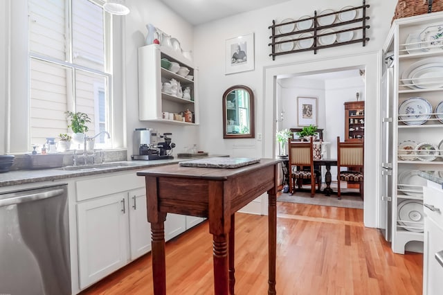 kitchen with sink, stainless steel dishwasher, white cabinetry, light stone counters, and light hardwood / wood-style floors