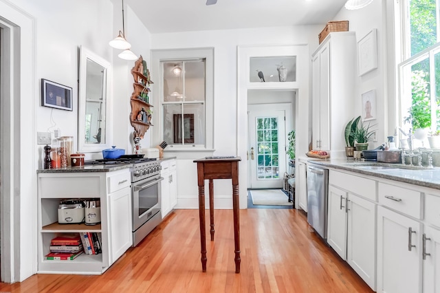 kitchen with white cabinetry, light stone counters, stainless steel appliances, and light wood-type flooring