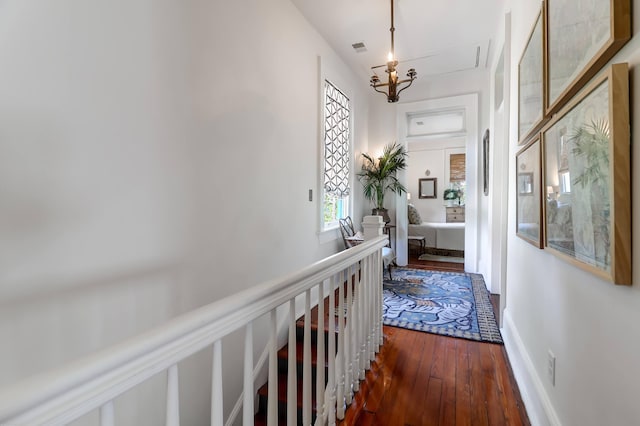 corridor featuring dark wood-type flooring and a notable chandelier