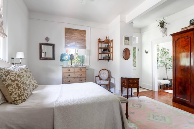 bedroom featuring beam ceiling and light hardwood / wood-style flooring