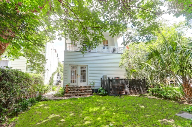 back of property with a lawn and a balcony