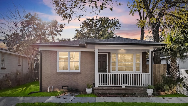 bungalow featuring a shingled roof, crawl space, brick siding, and covered porch