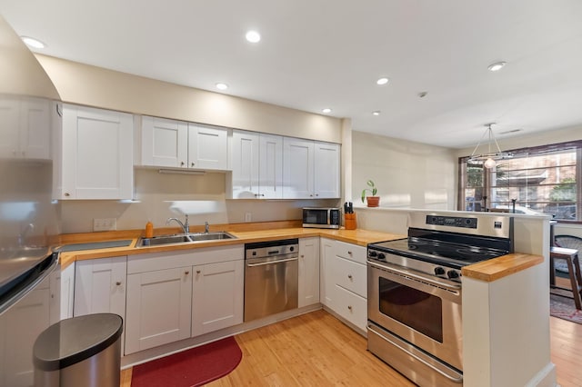 kitchen with a peninsula, light wood-style floors, stainless steel appliances, and a sink