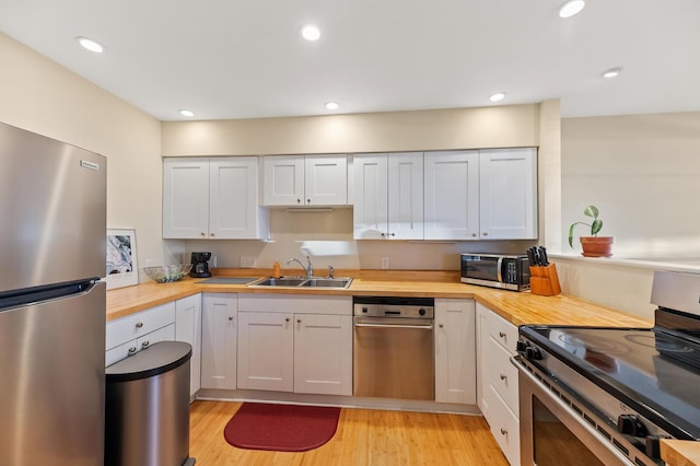 kitchen featuring light wood-style flooring, recessed lighting, stainless steel appliances, butcher block counters, and a sink