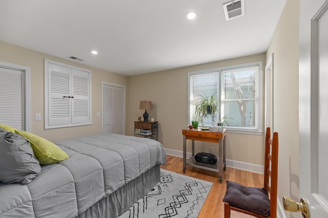 bedroom with recessed lighting, visible vents, baseboards, and wood finished floors