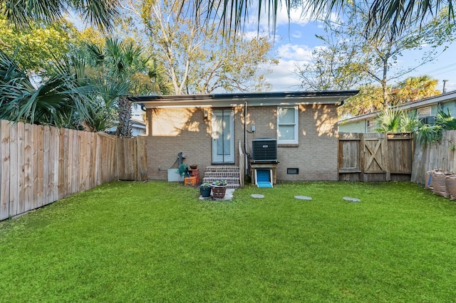 back of property featuring entry steps, a fenced backyard, crawl space, a yard, and brick siding