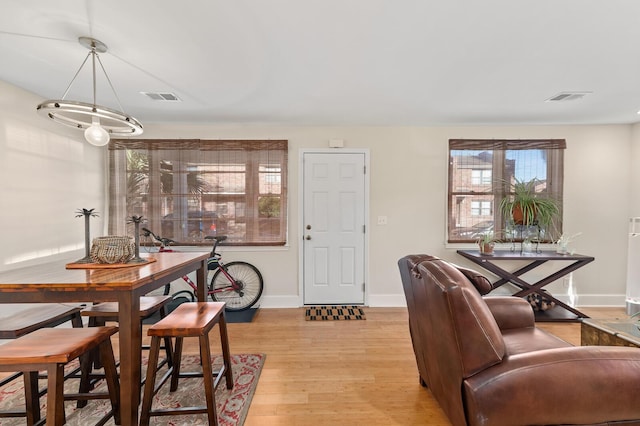 dining room with light wood-style floors, visible vents, and baseboards