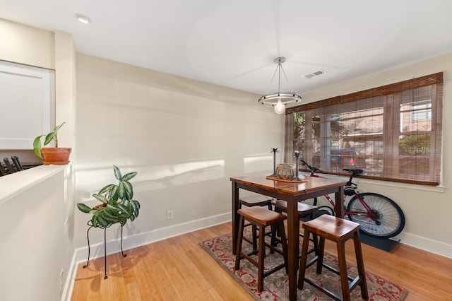 dining space featuring wood finished floors, visible vents, and baseboards