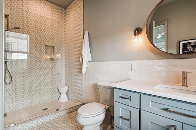 bathroom featuring a tile shower, vanity, toilet, and tile walls