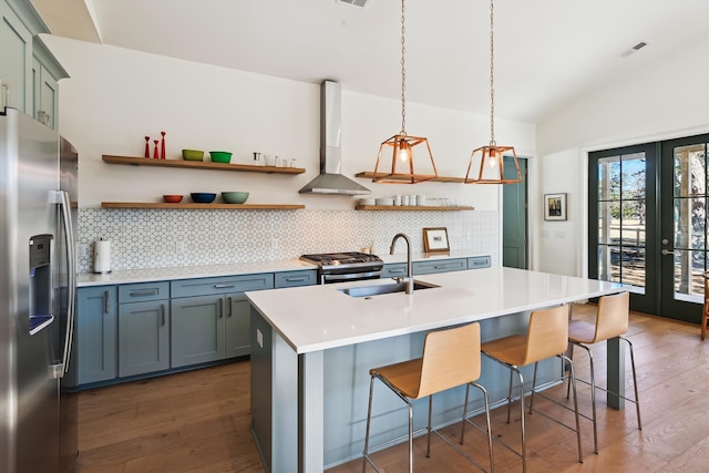 kitchen with pendant lighting, a kitchen breakfast bar, wall chimney range hood, sink, and appliances with stainless steel finishes