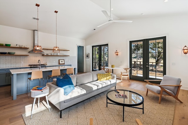 living room with french doors, light wood-type flooring, a healthy amount of sunlight, and sink