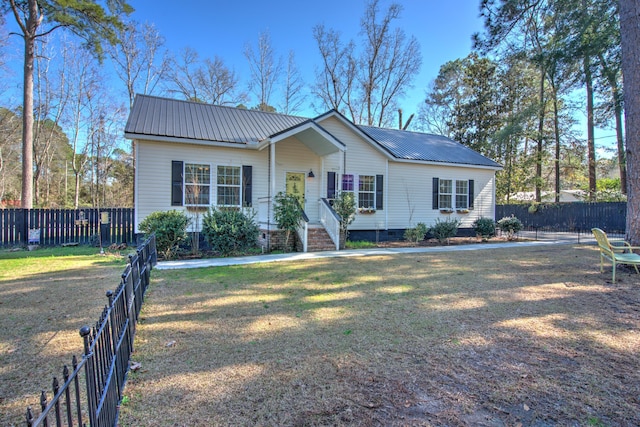 single story home with metal roof, a front lawn, and fence