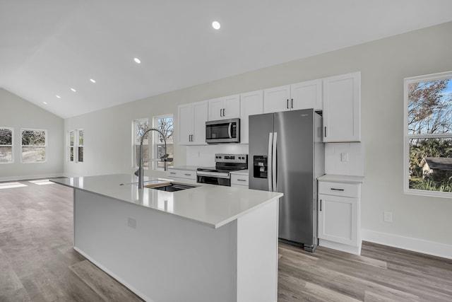 kitchen with appliances with stainless steel finishes, a kitchen island with sink, and white cabinetry