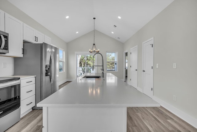 kitchen featuring a center island with sink, appliances with stainless steel finishes, hanging light fixtures, light countertops, and a sink