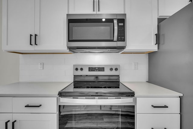 kitchen with appliances with stainless steel finishes, white cabinets, light countertops, and tasteful backsplash