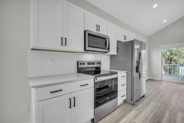 kitchen featuring tasteful backsplash, lofted ceiling, light countertops, appliances with stainless steel finishes, and white cabinetry