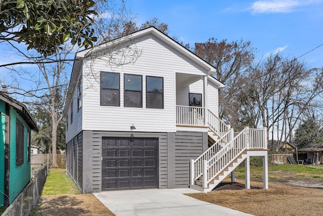 beach home featuring a garage, driveway, fence, and stairs