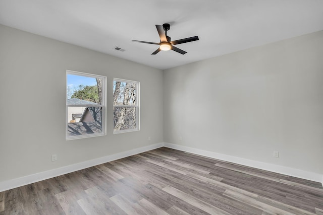 empty room featuring a ceiling fan, light wood-type flooring, visible vents, and baseboards