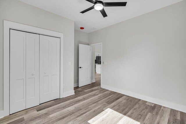 unfurnished bedroom featuring light wood-type flooring, a ceiling fan, baseboards, and a closet