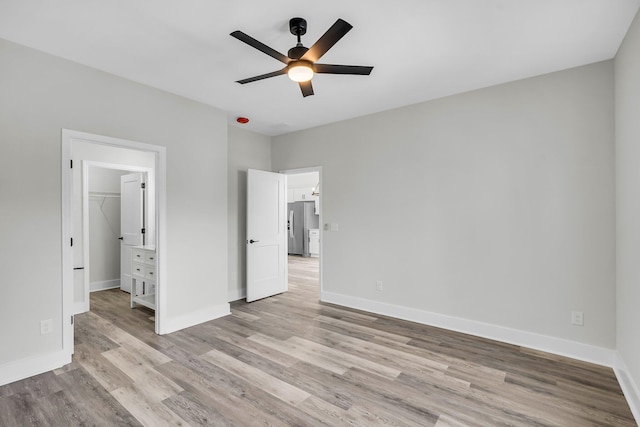 unfurnished bedroom with light wood-style floors, baseboards, and stainless steel fridge with ice dispenser